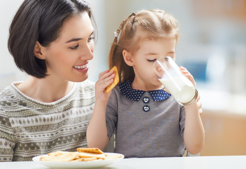 Mother looking at daughter eating breakfast Stock Photo