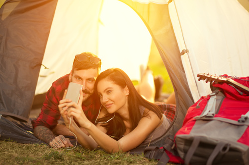 Self-portrait with mobile phone in camping tent Stock Photo
