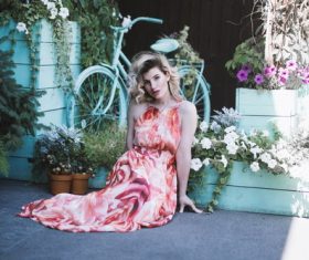 Sitting woman in front of the flowerbed Stock Photo