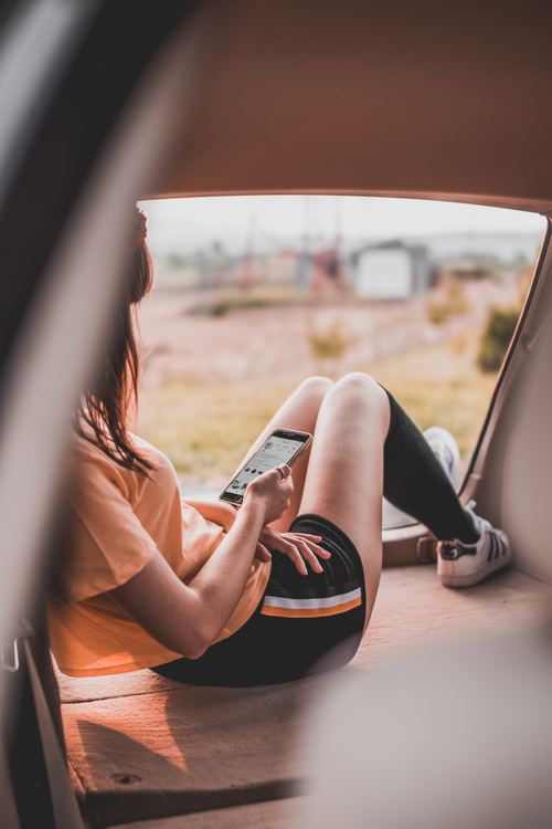 Stock Photo Girl looking at mobile phone in camping tent