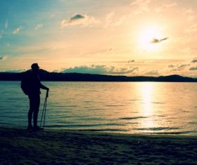 Stock Photo Man watching the sunrise by the sea