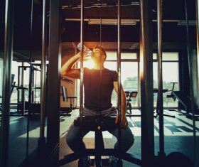 Stock Photo Young male sitting on sports equipment drinking water