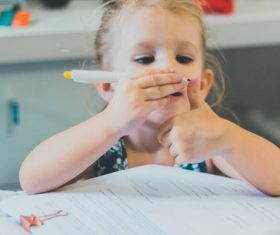 The little girl painted her thumb with an oil pen Stock Photo