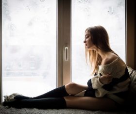 Unhappy girl sitting at the window Stock Photo