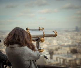 Woman looking at city landscape with telescope Stock Photo