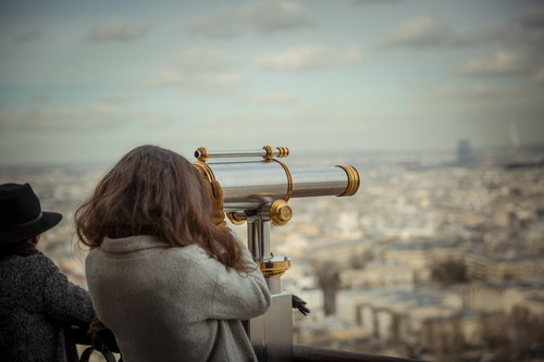 Woman looking at city landscape with telescope Stock Photo