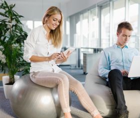 Woman sitting on fitness ball looking at mobile phone Stock Photo