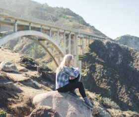 Woman sitting on steep rock Stock Photo