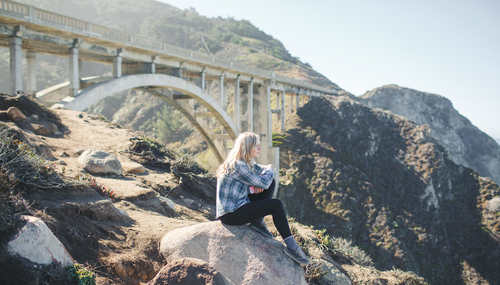 Woman sitting on steep rock Stock Photo