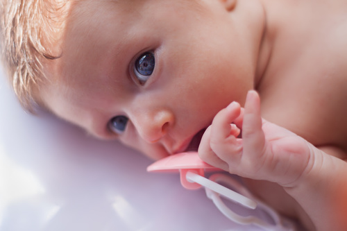 Baby holding a pacifier Stock Photo