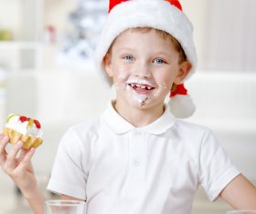 Child wearing christmas hat eating cake Stock Photo 01