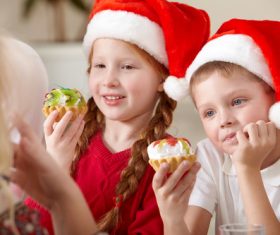 Child wearing christmas hat eating cake Stock Photo 03