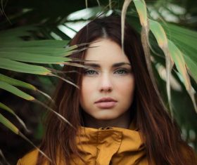 Girl standing under the leaves of plants Stock Photo