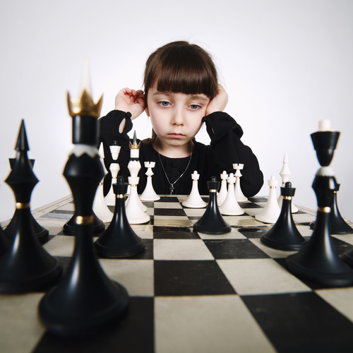 Little girl concentrates on playing Chess Stock Photo