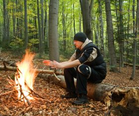 Man in the wild roasting fire Stock Photo