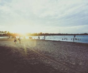Stock Photo Backlit shot of people playing on the beach