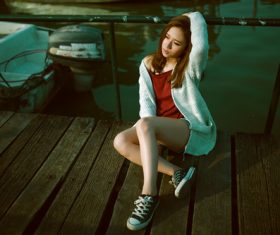 Stock Photo Charming girl sitting on the dock