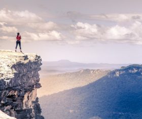 Stock Photo Girl standing on the top of the mountain and photographing nature