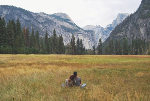 Stock Photo Lovers sitting on the grass looking at the distant landscape