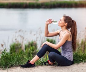 Stock Photo Pretty girl sitting on the ground for rest and water