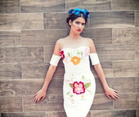 Stock Photo Woman in floral dress stands in front of wooden background