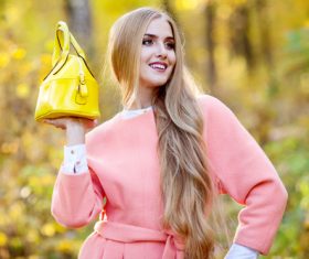 Woman in pink coat holds yellow handbag pose Stock Photo