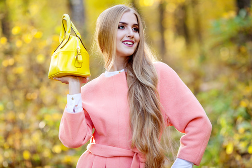 Woman in pink coat holds yellow handbag pose Stock Photo
