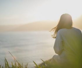 Beautiful girl sitting high up looking at the sea Stock Photo