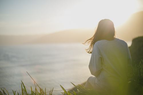 Beautiful girl sitting high up looking at the sea Stock Photo