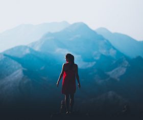 Beautiful girl standing on the top of the mountain back shadow Stock Photo