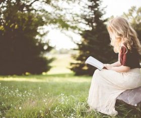Blonde girl reading book in the park Stock Photo
