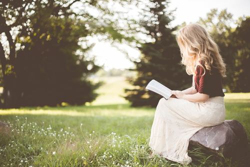 Blonde girl reading book in the park Stock Photo