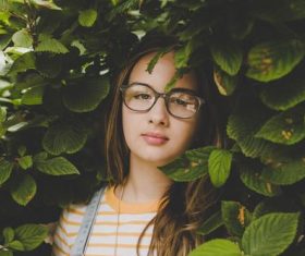 Girl hidden among the green leaves Stock Photo