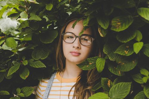 Girl hidden among the green leaves Stock Photo