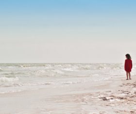 Stock Photo Little girl watching the tide on the beach