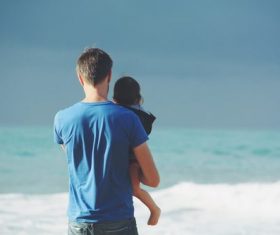 Stock Photo Man holding daughter watching the sea