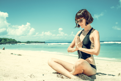 Stock Photo Woman meditating while sitting on the beach