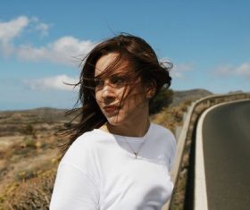 Stock Photo Woman sitting on the highway guardrail