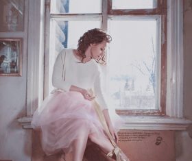 Woman sitting on the window sill with bow Stock Photo