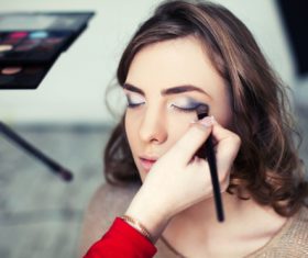 Beautician draws eye shadow on model Stock Photo