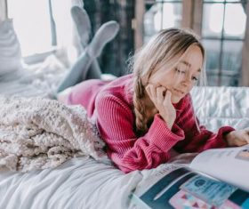 Girl reading book in bed Stock Photo