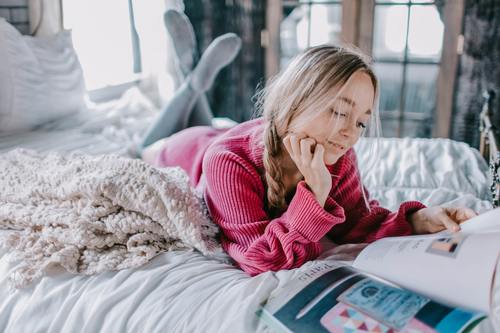 Girl reading book in bed Stock Photo