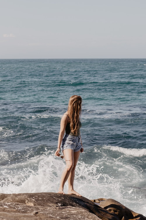 Girl standing on the reef looking at the sea Stock Photo