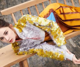 Pretty girl in fashionable clothes lying on wooden chair Stock Photo