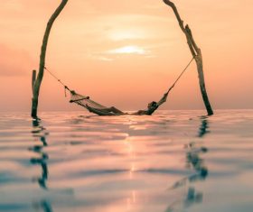 Woman lying in hammock in the sea Stock Photo