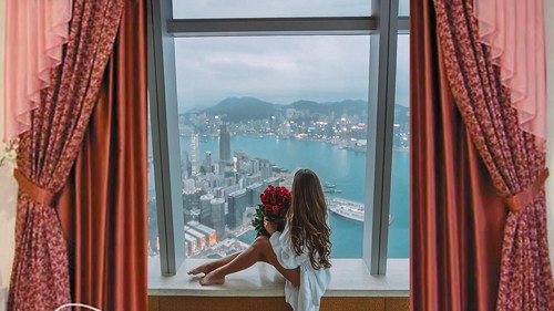 Stock Photo Girl sitting on the window sill holding rose
