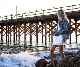 Stock Photo Girl standing on the sea reef looking at the sea
