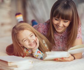 Young mother reads fairy tale book to daughter Stock Photo 01