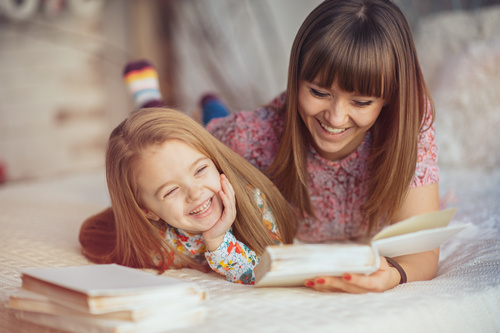 Young mother reads fairy tale book to daughter Stock Photo 01