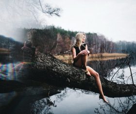 Art photo woman sitting on the trunk of the lake Stock Photo